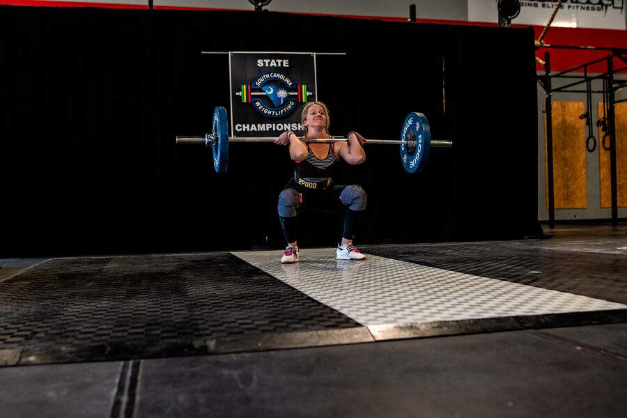 Coach Jess at the bottom of a heavy squat at a weightlifting competition